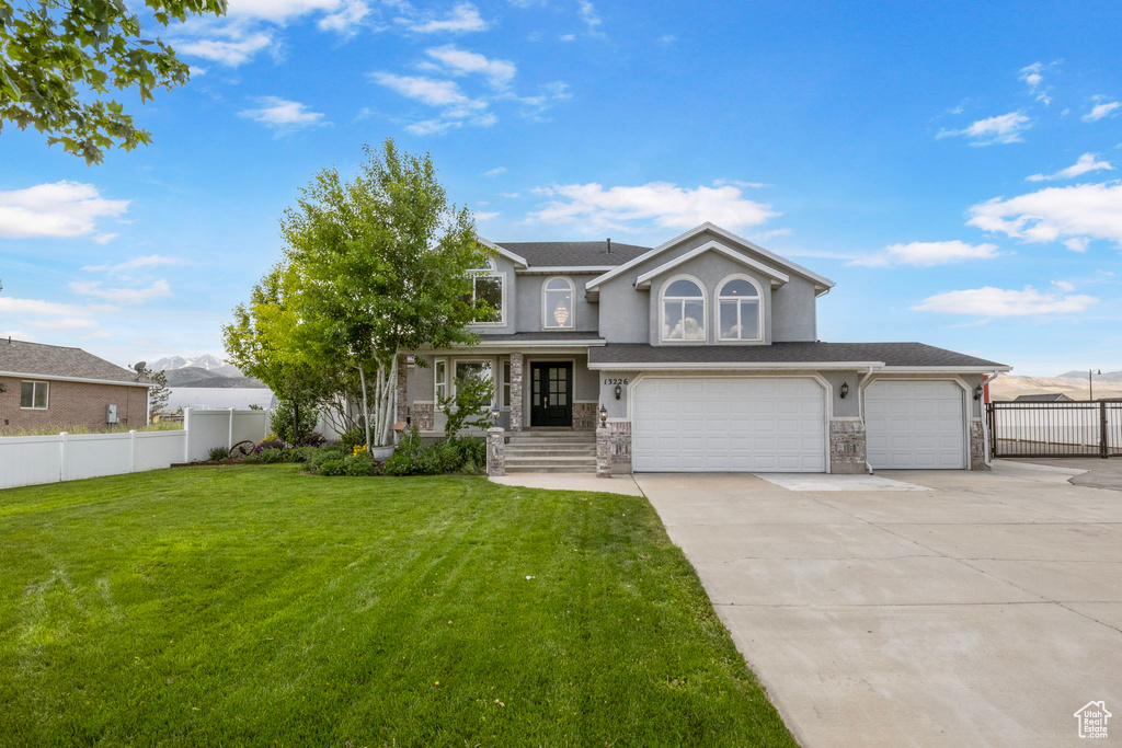 View of front of property with driveway, a garage, stone siding, and stucco siding