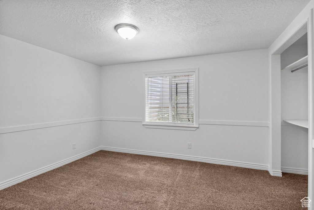 Unfurnished bedroom featuring a textured ceiling, carpet, and baseboards