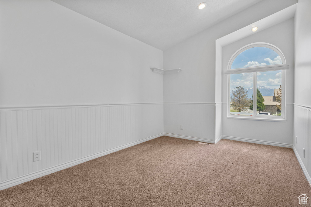 Carpeted spare room featuring vaulted ceiling, baseboards, and recessed lighting