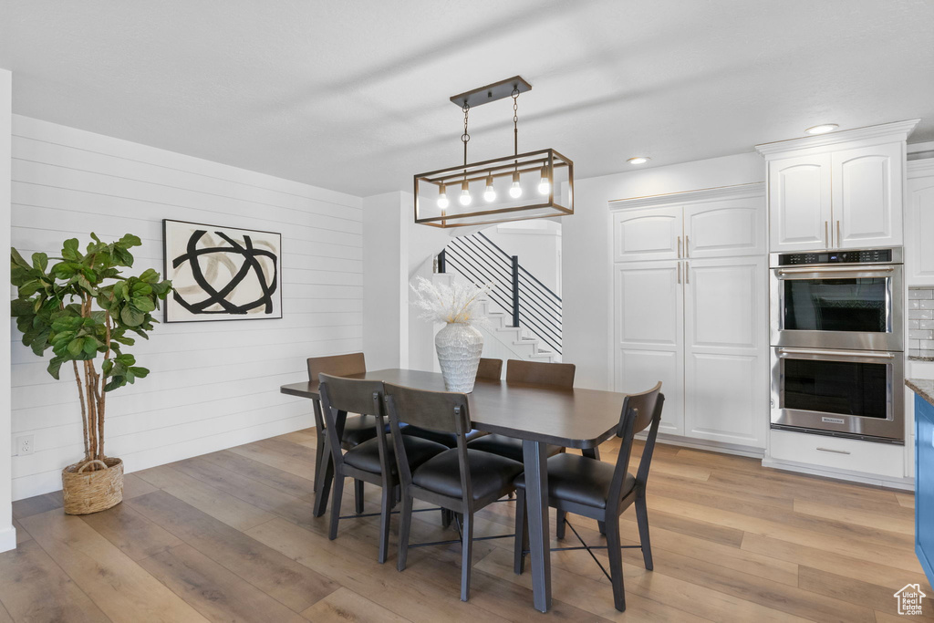 Dining space with stairs, light wood-type flooring, recessed lighting, and wooden walls