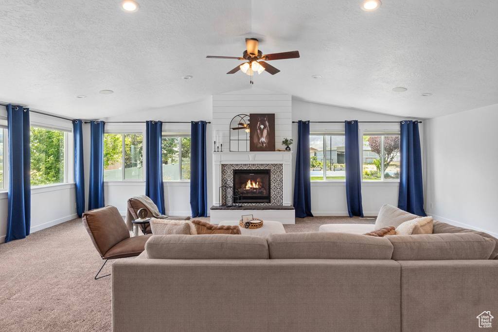 Living room with lofted ceiling, a textured ceiling, baseboards, light colored carpet, and a fireplace