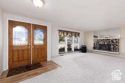 Entryway with a fireplace with raised hearth and carpet