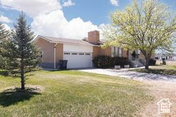 View of front facade with a front yard, a garage, and a chimney