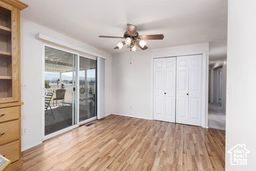 Unfurnished bedroom featuring access to outside, wood finished floors, ceiling fan, and a closet