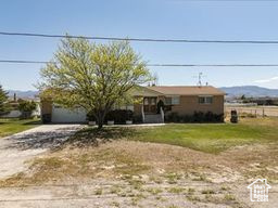 View of front facade with dirt driveway and a front lawn