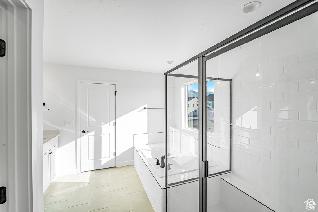 Full bath with a bath, a shower stall, vanity, and tile patterned flooring