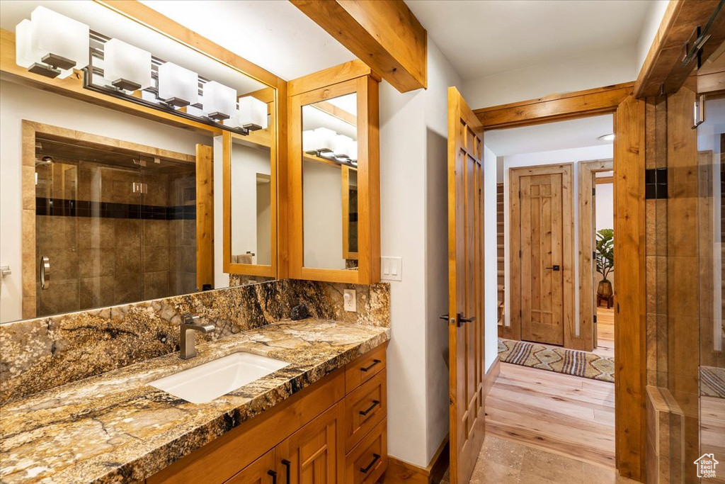 Bathroom with vanity, a tile shower, tasteful backsplash, and wood finished floors