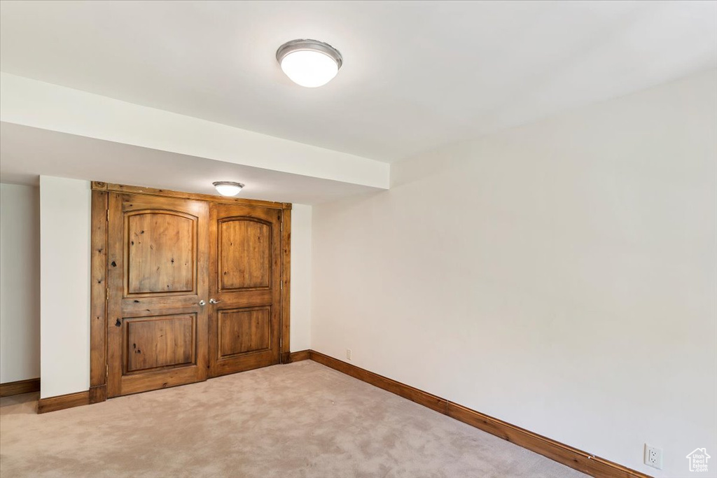 Unfurnished bedroom with light carpet and baseboards