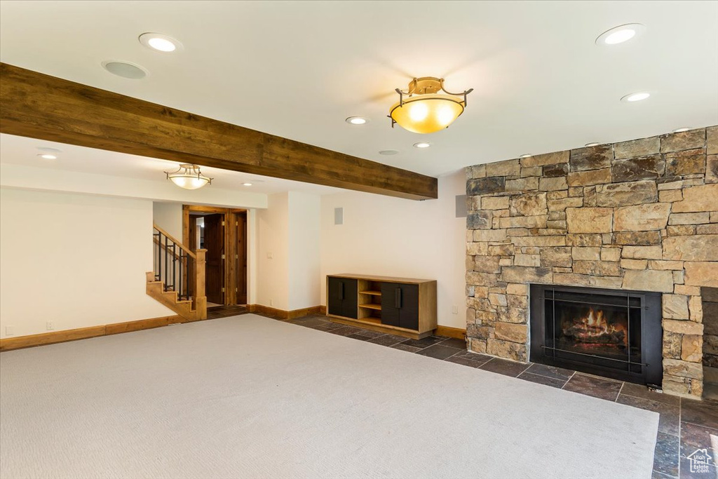 Unfurnished living room with recessed lighting, stairs, baseboards, a stone fireplace, and beam ceiling