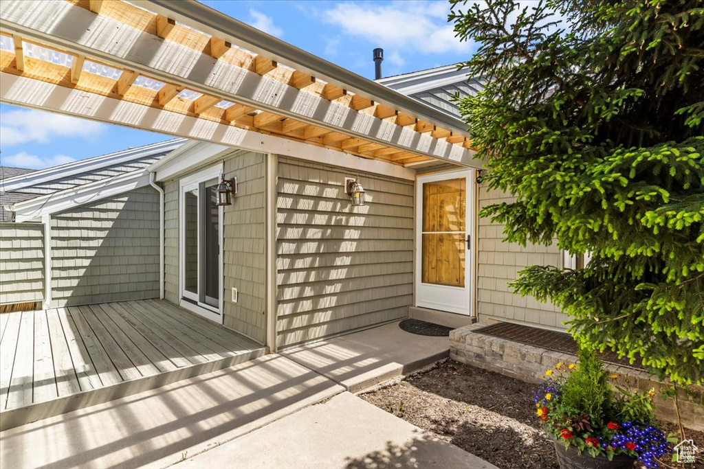 Doorway to property featuring a deck and a pergola