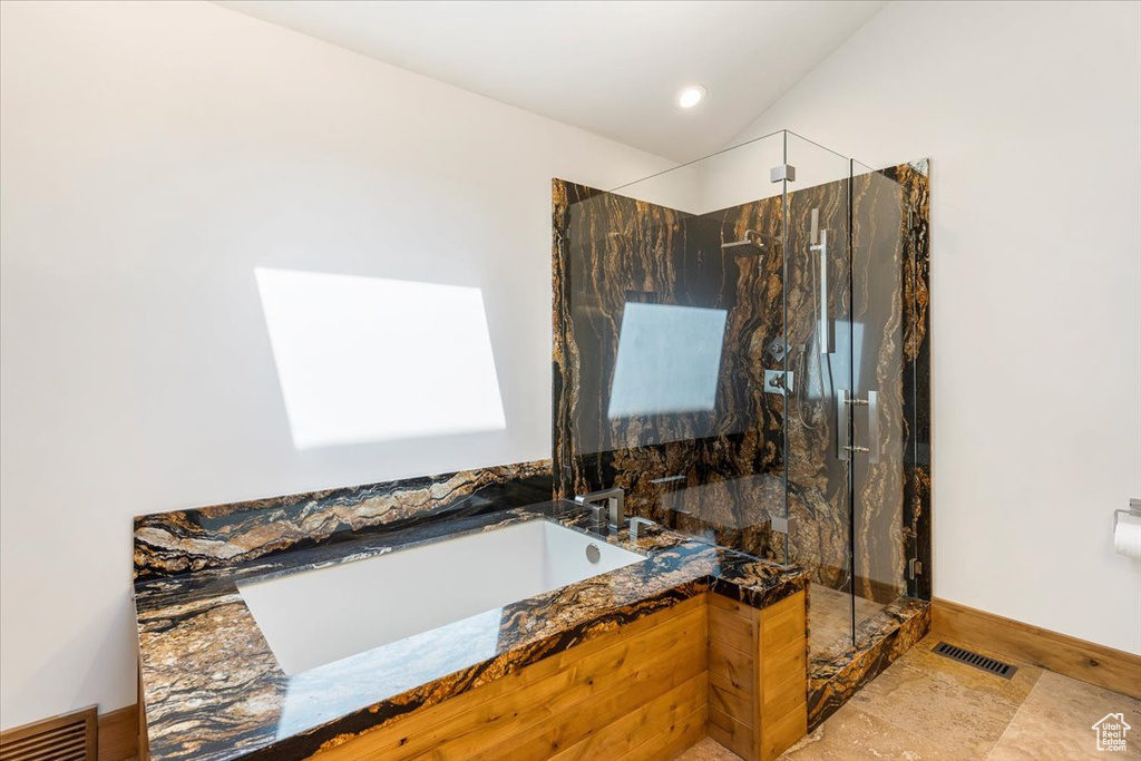 Full bathroom with a marble finish shower, a garden tub, vaulted ceiling, and baseboards