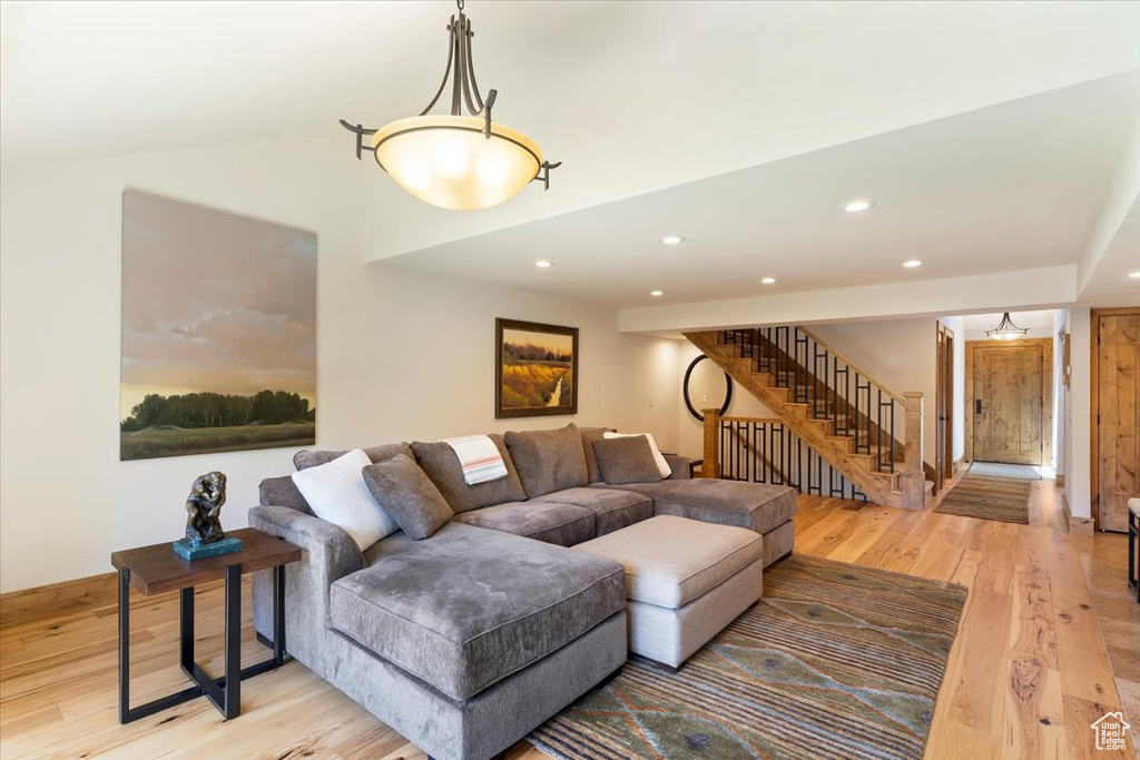 Living area featuring light wood-style flooring, stairs, recessed lighting, baseboards, and lofted ceiling