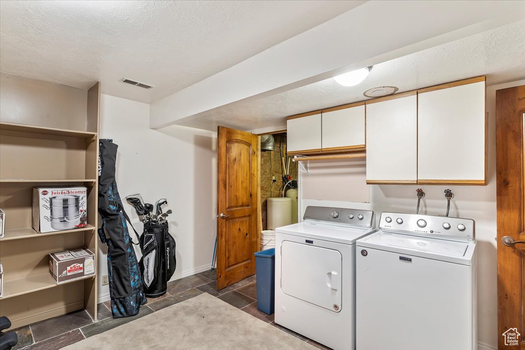 Laundry room featuring cabinet space, washer and dryer, and a textured ceiling