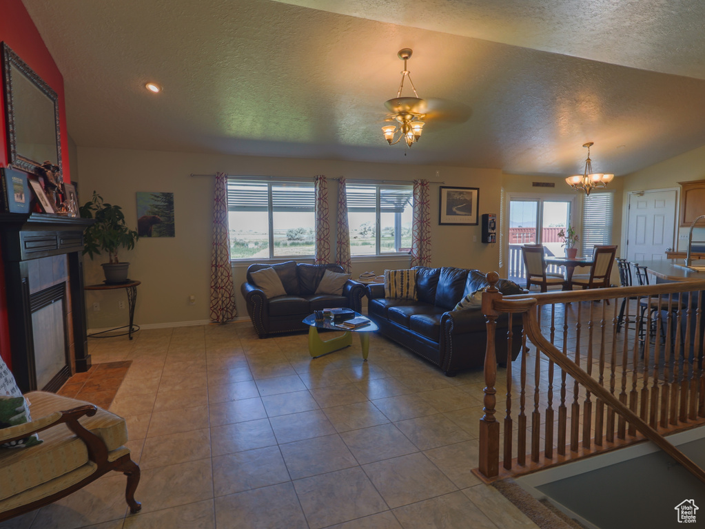 Tiled living room featuring a chandelier, a tiled fireplace, plenty of natural light, a textured ceiling, and baseboards