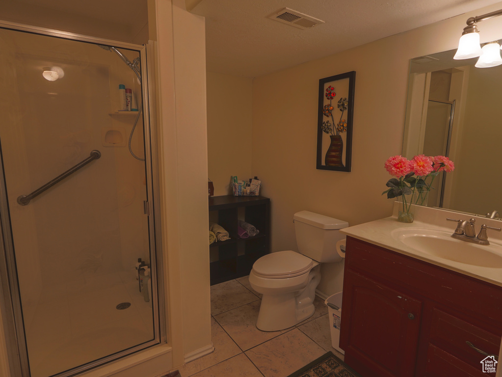Full bath with vanity, a stall shower, tile patterned floors, and toilet