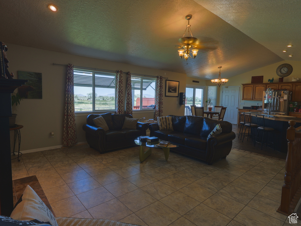 Tiled living room with a chandelier, a textured ceiling, lofted ceiling, and baseboards