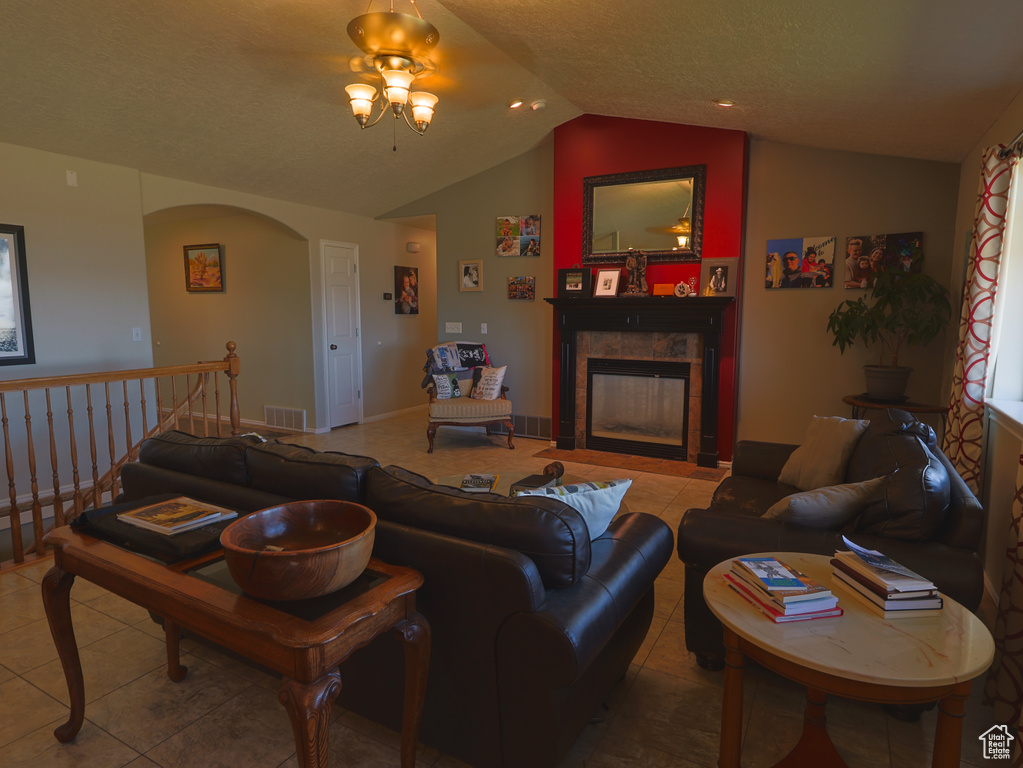 Tiled living area with lofted ceiling, a tile fireplace, arched walkways, and a ceiling fan