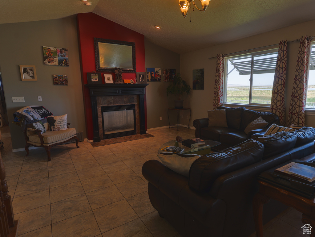 Living room with lofted ceiling, a tile fireplace, tile patterned floors, and baseboards