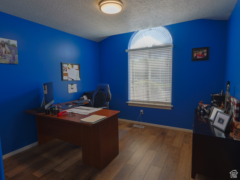 Home office with a textured ceiling, wood finished floors, and baseboards