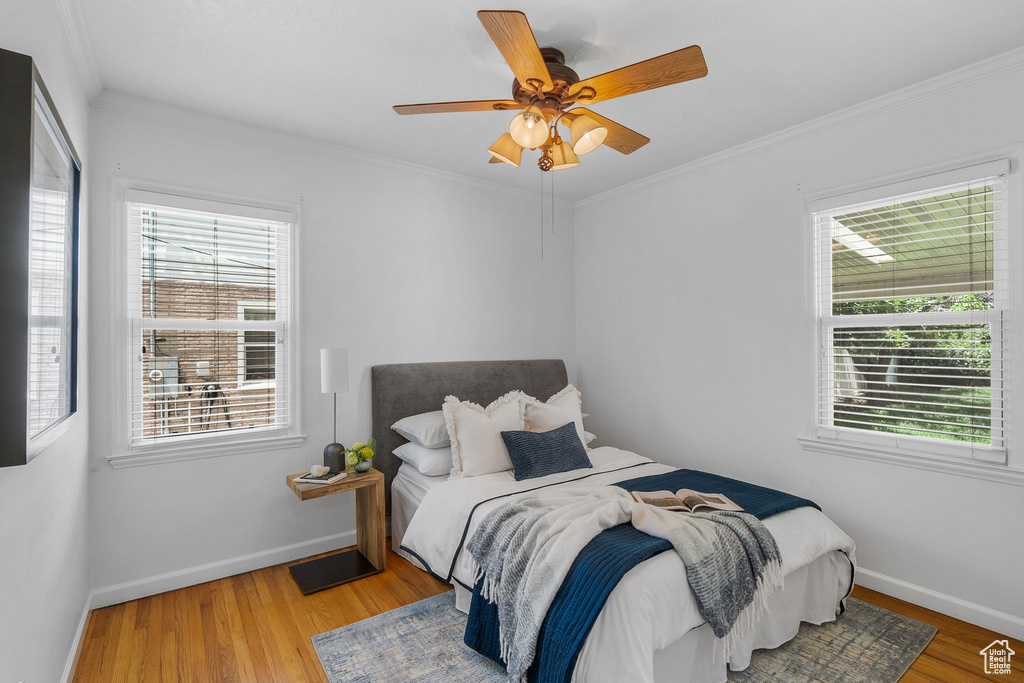 Bedroom with multiple windows, baseboards, wood finished floors, and crown molding