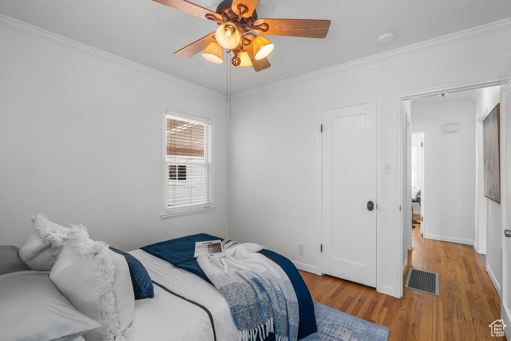 Bedroom with light wood-style floors, crown molding, baseboards, and ceiling fan
