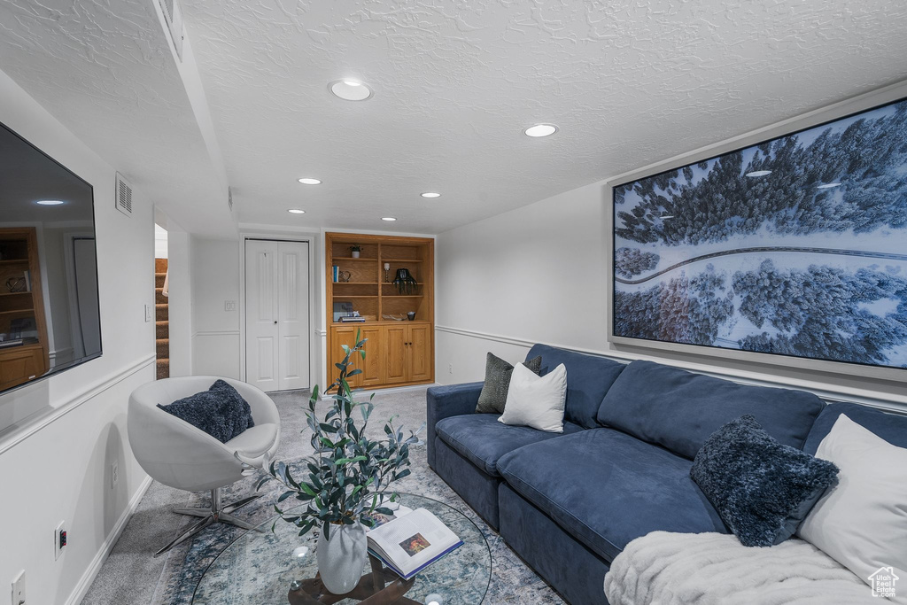 Carpeted living area featuring baseboards, recessed lighting, and a textured ceiling
