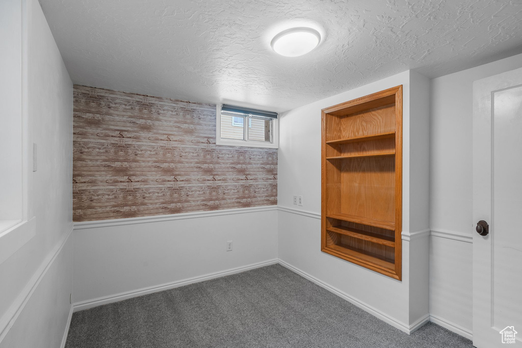 Carpeted spare room featuring a textured ceiling and wooden walls