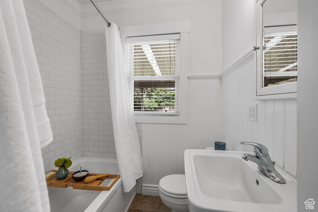 Bathroom with a sink, shower / bath combination with curtain, toilet, crown molding, and tile patterned flooring