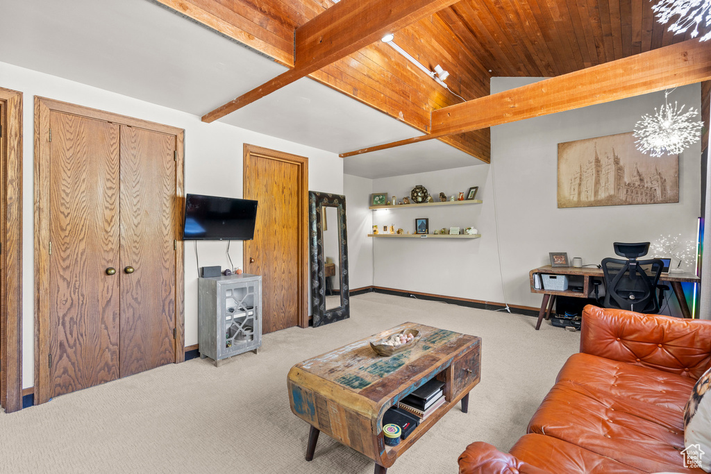 Living area with carpet floors, wooden ceiling with exposed beams, an office area, and baseboards