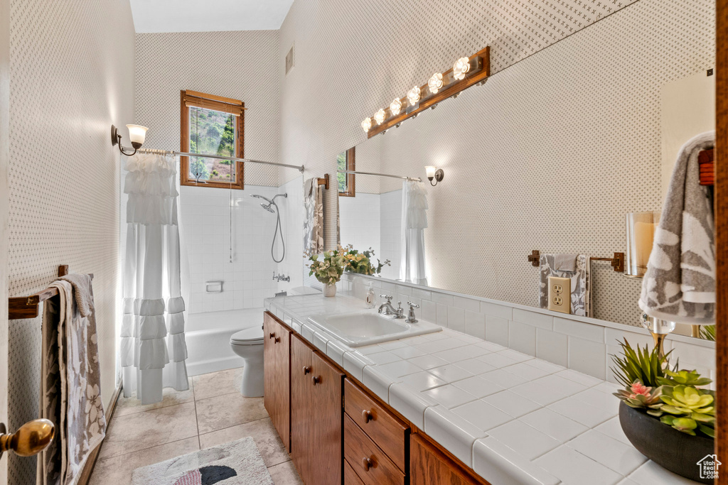 Bathroom with vanity, shower / tub combo with curtain, toilet, and tile patterned floors