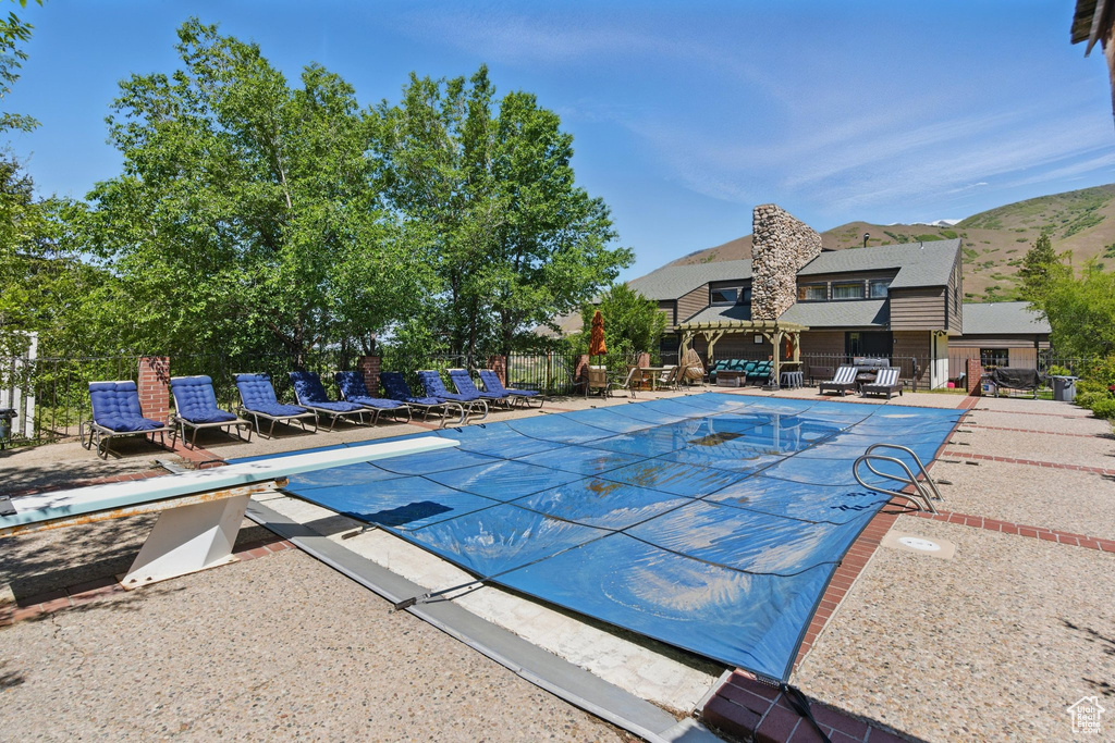 View of pool with a diving board and a patio area
