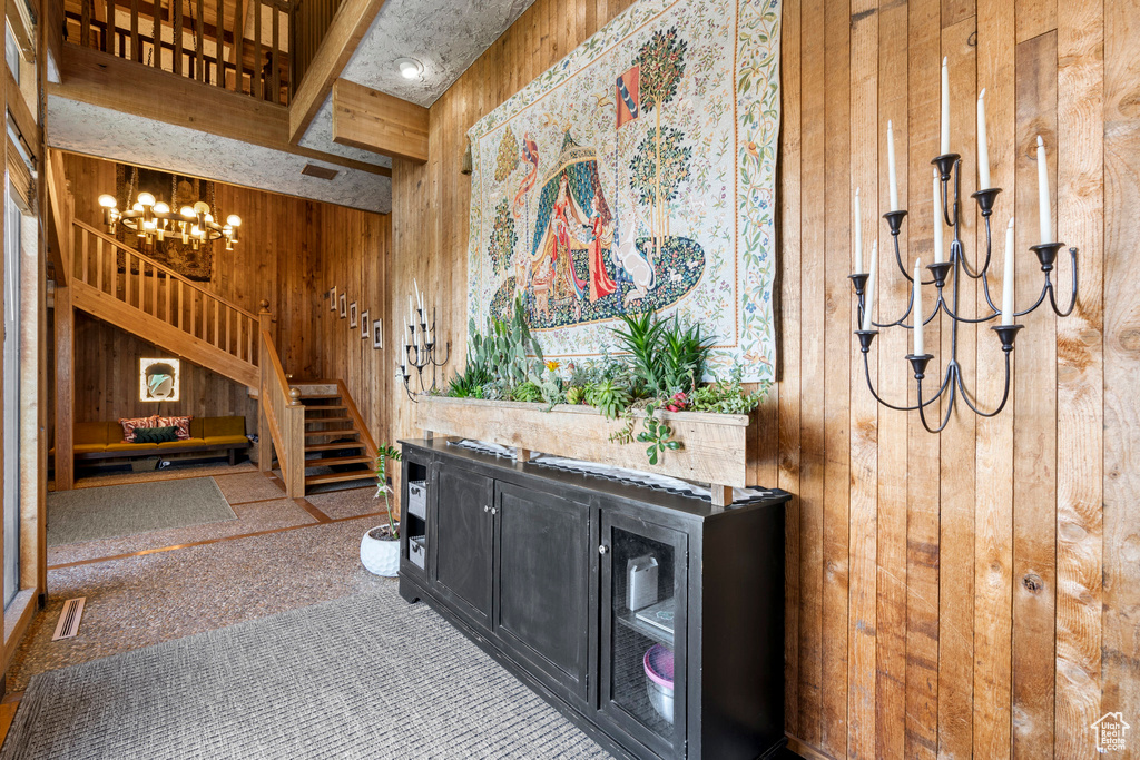 Carpeted living room featuring wooden walls, a chandelier, and stairway