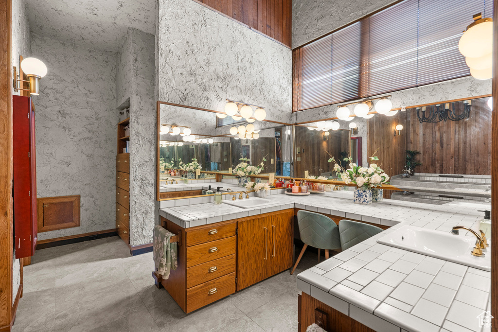 Full bath featuring a high ceiling, double vanity, and a chandelier