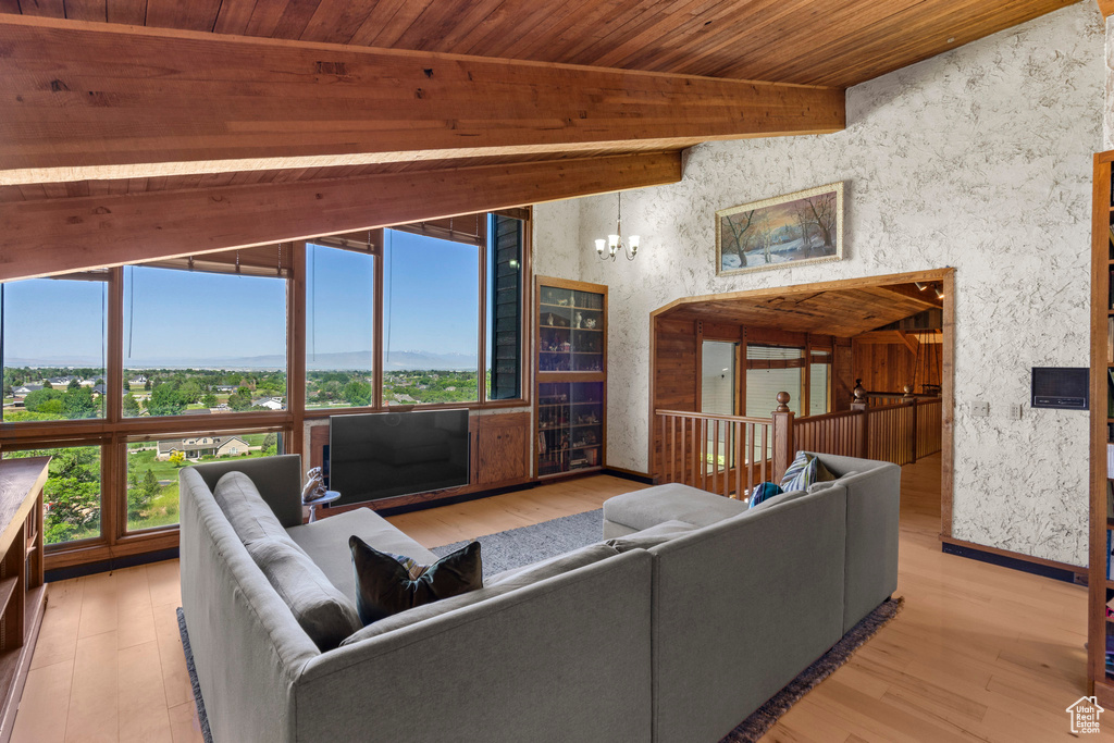 Living area featuring wood finished floors, wood ceiling with exposed beams, baseboards, and a chandelier