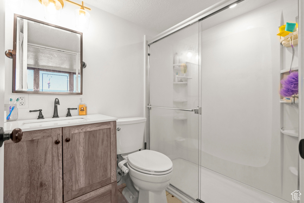 Full bathroom featuring vanity, a stall shower, toilet, and a textured ceiling