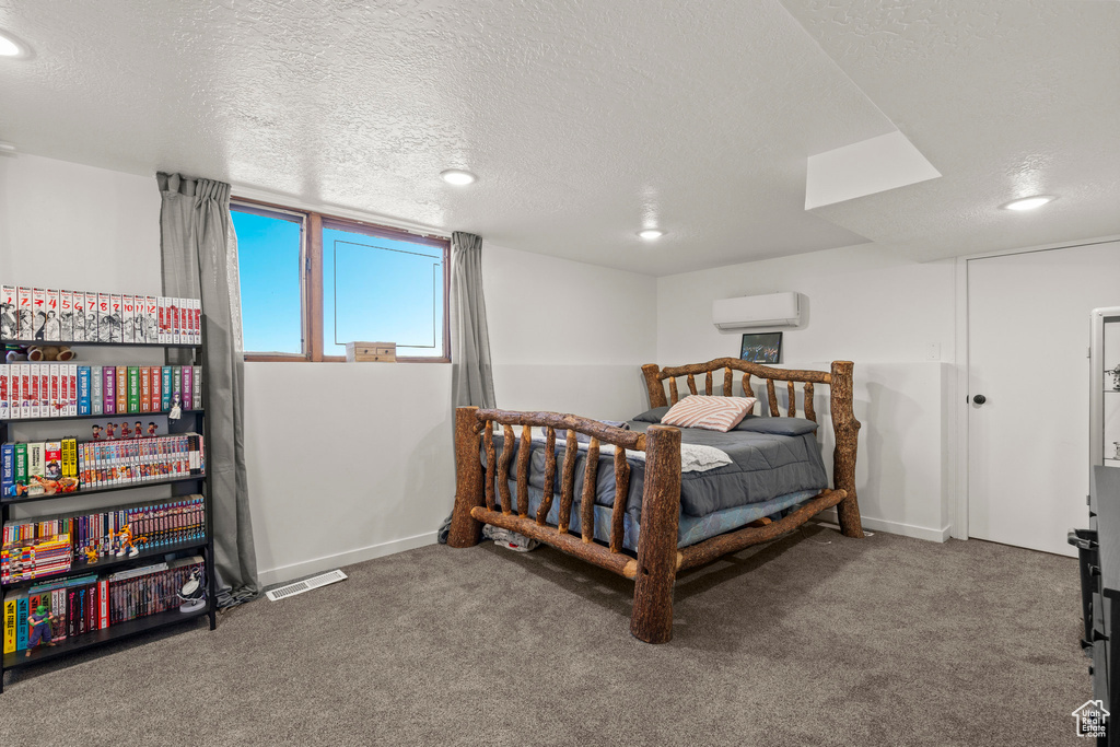 Bedroom with a wall mounted air conditioner, carpet floors, a textured ceiling, recessed lighting, and baseboards