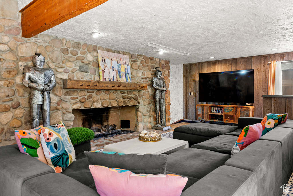 Living area featuring a fireplace, a textured ceiling, and wooden walls