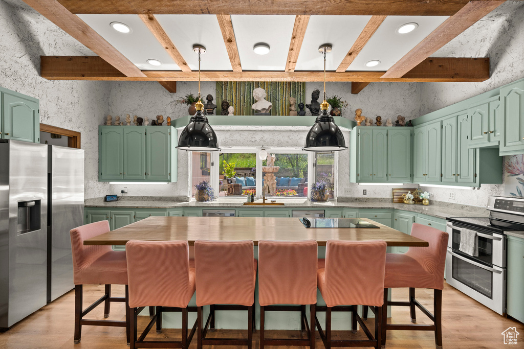 Kitchen with appliances with stainless steel finishes, green cabinets, light wood-style floors, beam ceiling, and light countertops