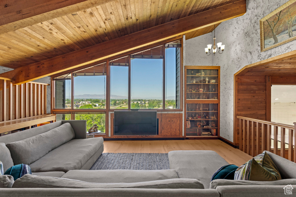 Living room featuring wood finished floors, a chandelier, and wallpapered walls