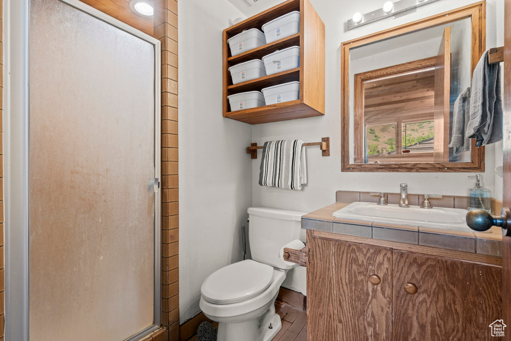 Bathroom featuring a stall shower, vanity, and toilet