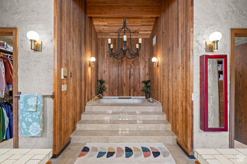 Stairway featuring a chandelier, a textured wall, and beamed ceiling