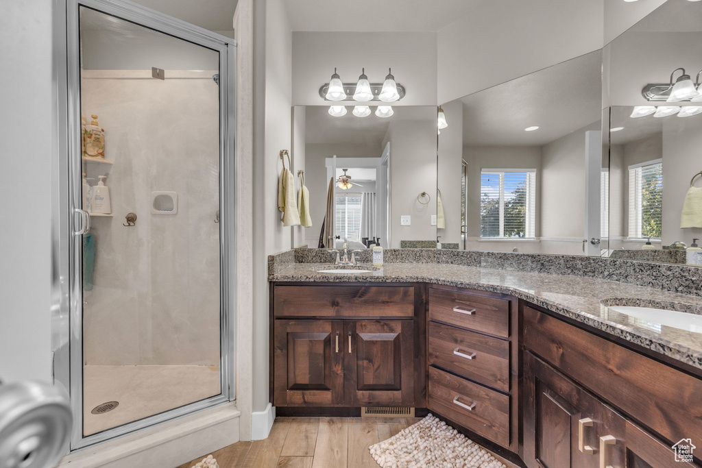 Full bath featuring a stall shower, double vanity, and wood finished floors