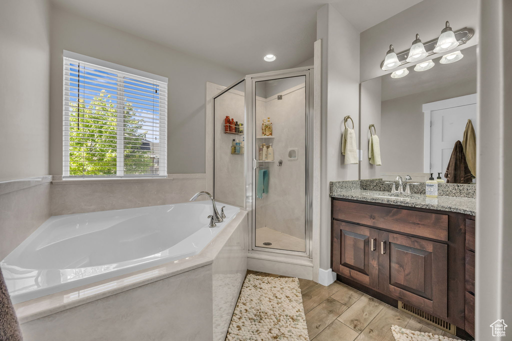 Bathroom with vanity, a stall shower, and a garden tub