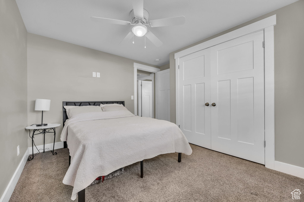 Bedroom with carpet, baseboards, ceiling fan, and a closet