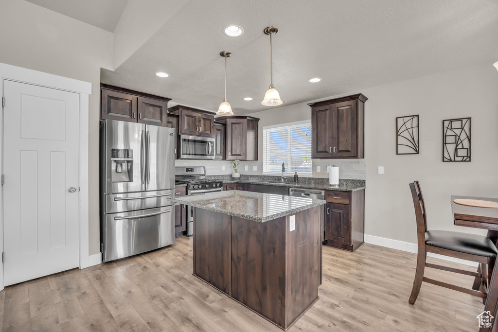 Kitchen with appliances with stainless steel finishes, dark brown cabinets, a sink, baseboards, and recessed lighting