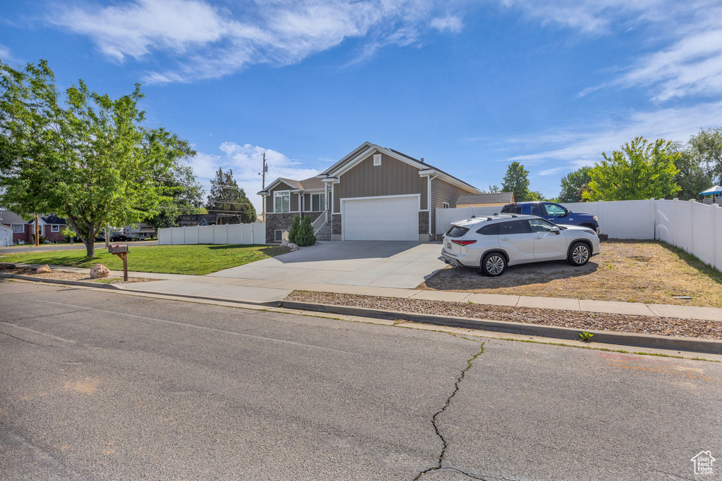 Single story home with driveway, an attached garage, and stone siding