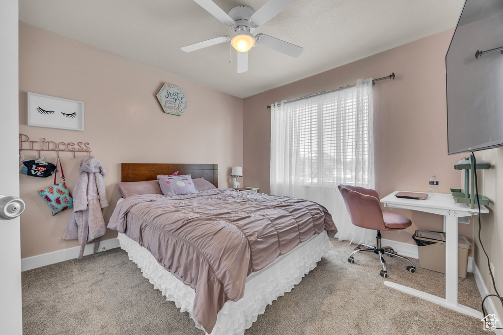 Carpeted bedroom with baseboards, ceiling fan, and an office area