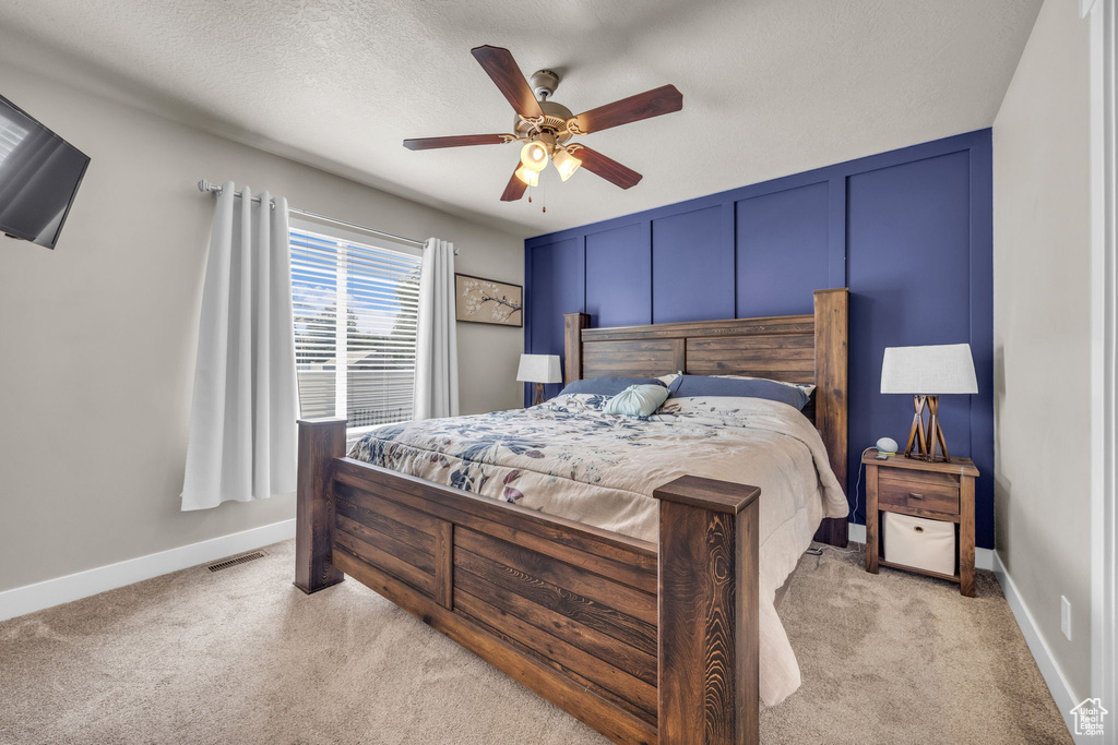 Bedroom with light carpet, ceiling fan, and baseboards
