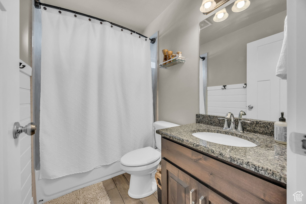 Full bathroom featuring vanity, toilet, and shower / bathtub combination with curtain