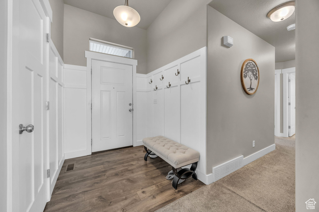 Mudroom with dark wood finished floors, baseboards, and a towering ceiling